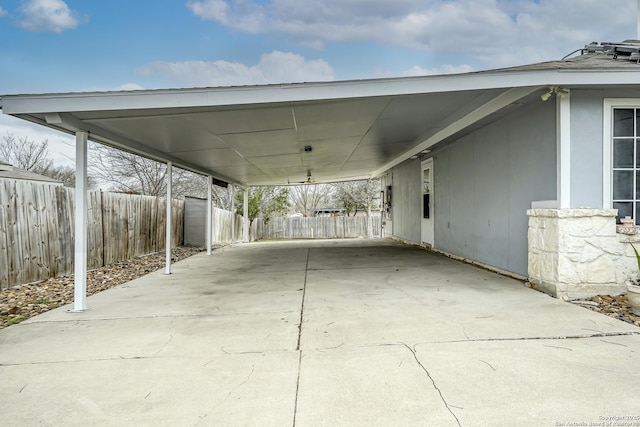 view of patio featuring driveway, an attached carport, and fence