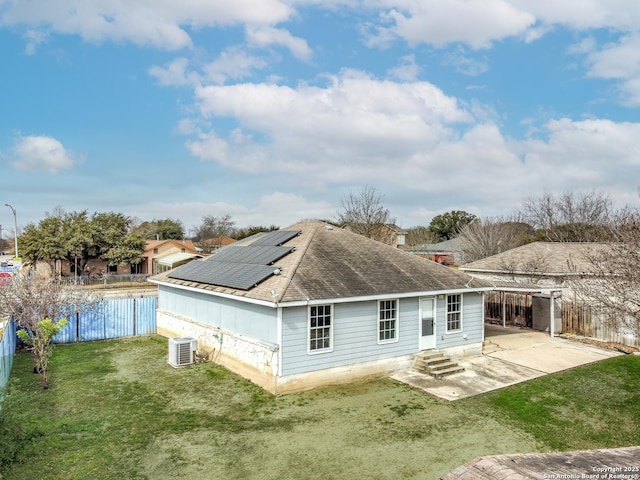 rear view of house with a yard, a patio, central air condition unit, entry steps, and roof mounted solar panels