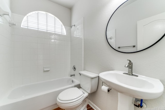 full bathroom featuring a textured wall, shower / bathing tub combination, toilet, a sink, and baseboards