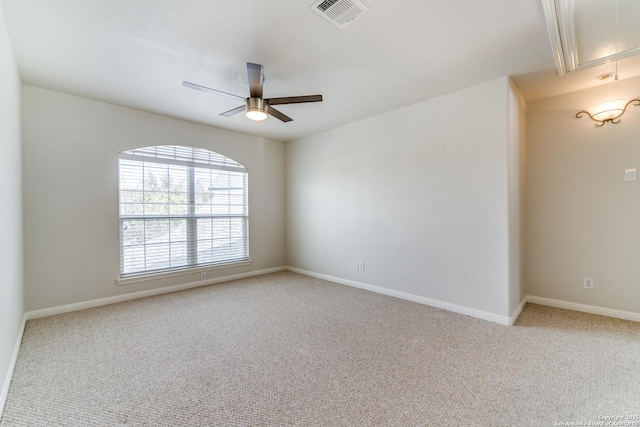 spare room with attic access, baseboards, visible vents, a ceiling fan, and light colored carpet