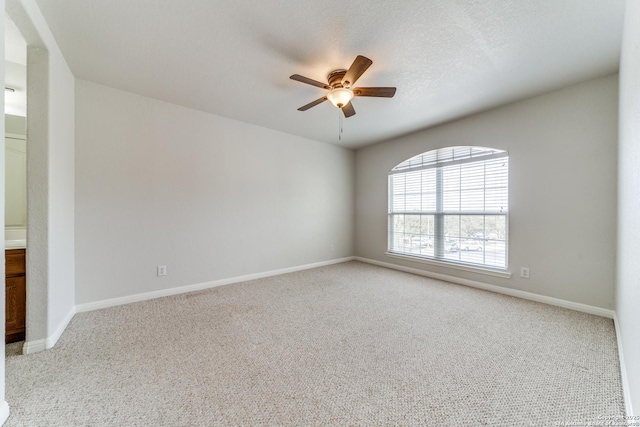 carpeted empty room featuring ceiling fan, a textured ceiling, and baseboards