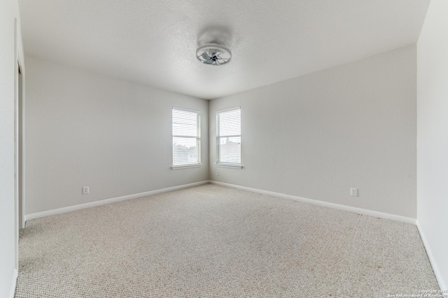 carpeted empty room featuring a textured ceiling and baseboards