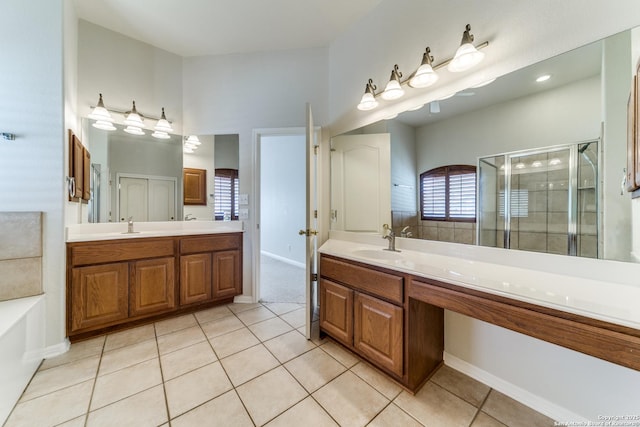 bathroom with a stall shower, tile patterned flooring, two vanities, and a sink