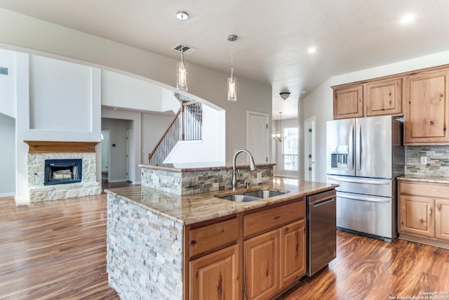 kitchen with visible vents, decorative backsplash, appliances with stainless steel finishes, a fireplace, and a sink