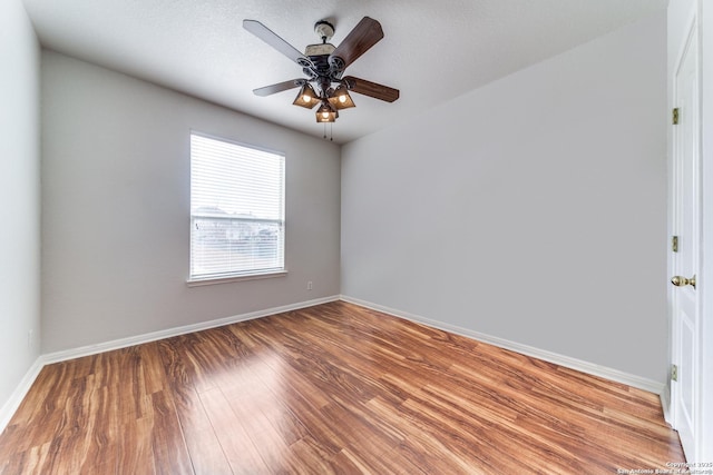 unfurnished room with ceiling fan, wood finished floors, and baseboards