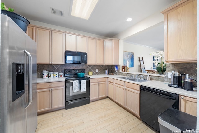 kitchen featuring visible vents, light countertops, black appliances, light brown cabinets, and a sink