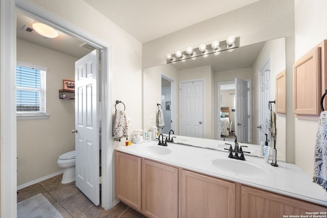 ensuite bathroom featuring connected bathroom, toilet, a sink, visible vents, and double vanity