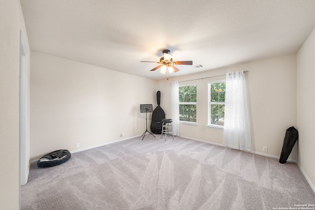 interior space with ceiling fan, carpet floors, a textured ceiling, and baseboards