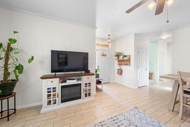 living area with wood finish floors, a ceiling fan, and crown molding