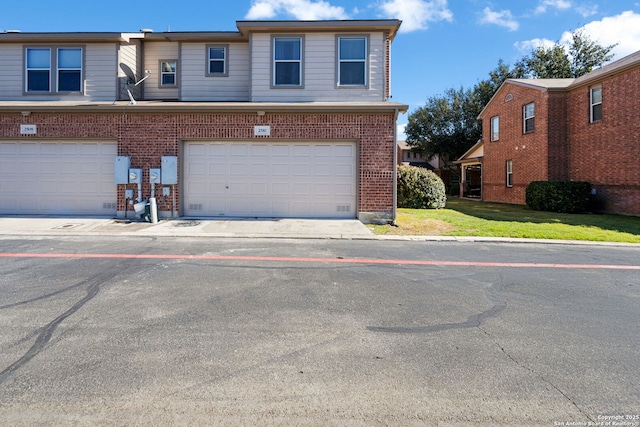 view of property with a garage, a front yard, and brick siding