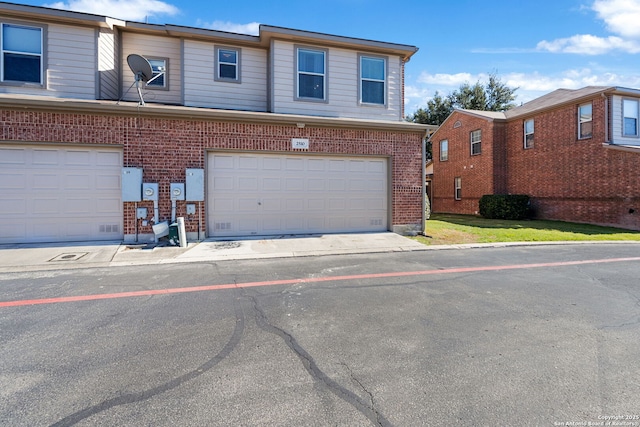 townhome / multi-family property featuring a garage and brick siding