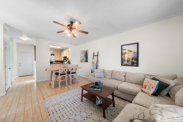 living area with ornamental molding, light wood-type flooring, ceiling fan, and baseboards