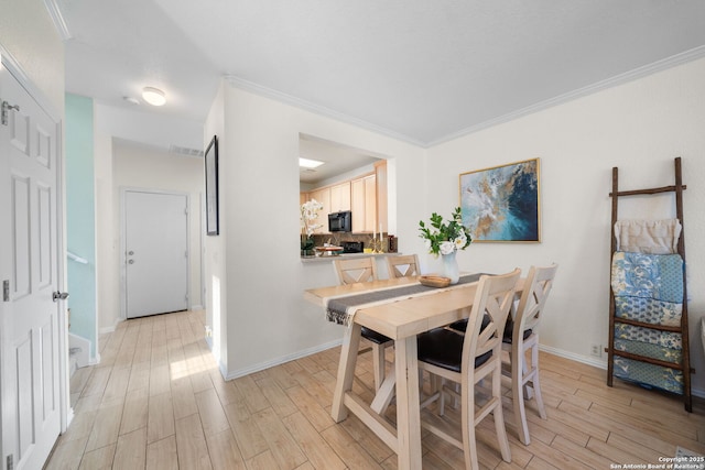 dining area with light wood finished floors, baseboards, and ornamental molding