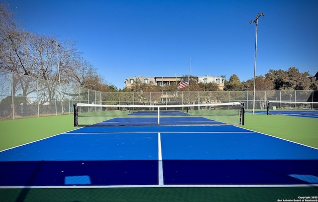 view of tennis court featuring community basketball court and fence