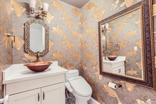 half bath with vanity, toilet, and wallpapered walls