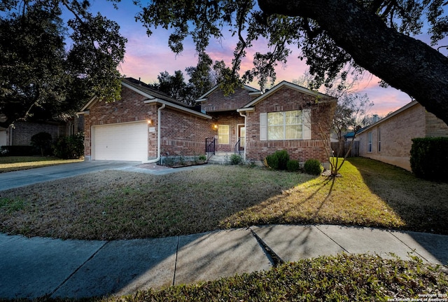 view of front of property featuring driveway, brick siding, a garage, and a front yard