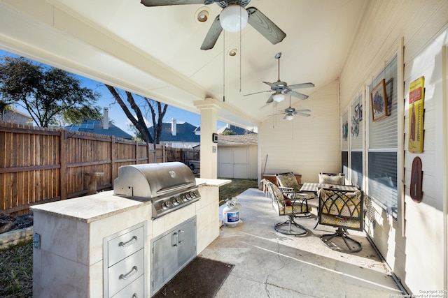 view of patio / terrace featuring grilling area, area for grilling, a ceiling fan, fence, and an outdoor structure