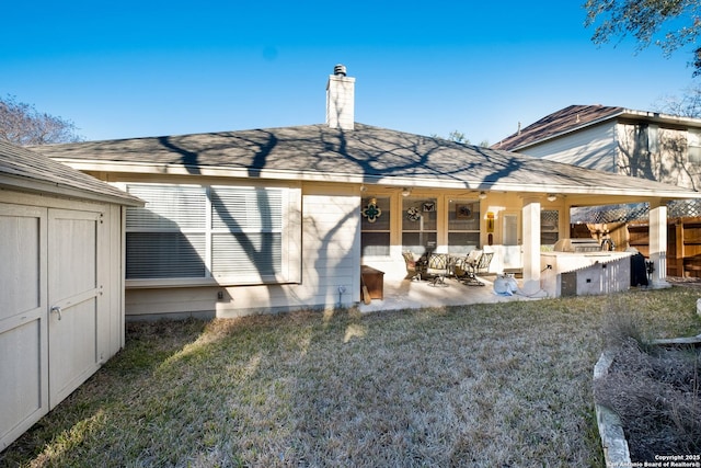 rear view of property with an outbuilding, fence, a storage unit, a chimney, and a patio area