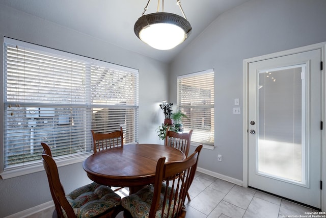 dining space with vaulted ceiling, light tile patterned floors, and baseboards