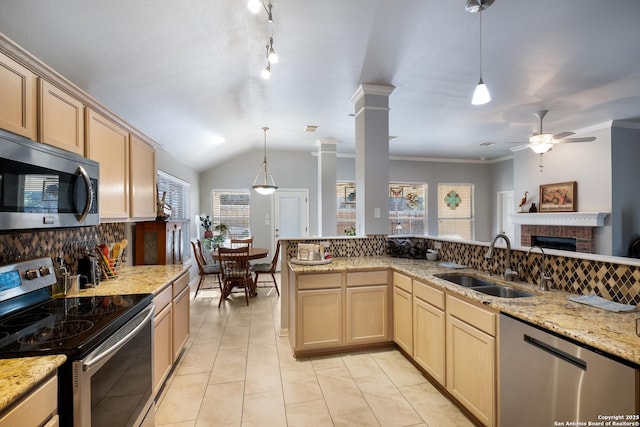 kitchen featuring a fireplace, stainless steel appliances, light brown cabinetry, a sink, and ornate columns