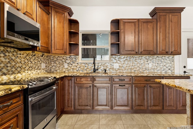 kitchen with open shelves, tasteful backsplash, appliances with stainless steel finishes, a sink, and light stone countertops