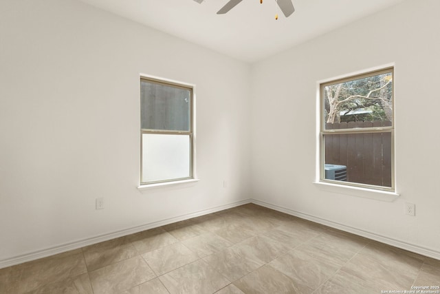 spare room with ceiling fan and baseboards