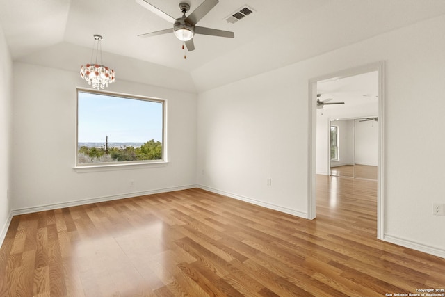 spare room featuring light wood-style flooring, visible vents, and vaulted ceiling