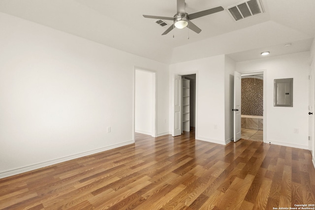 empty room with electric panel, visible vents, baseboards, and wood finished floors