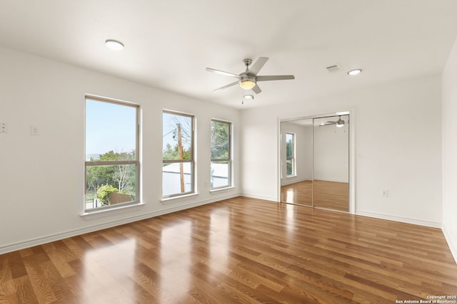 spare room with wood finished floors, visible vents, and baseboards