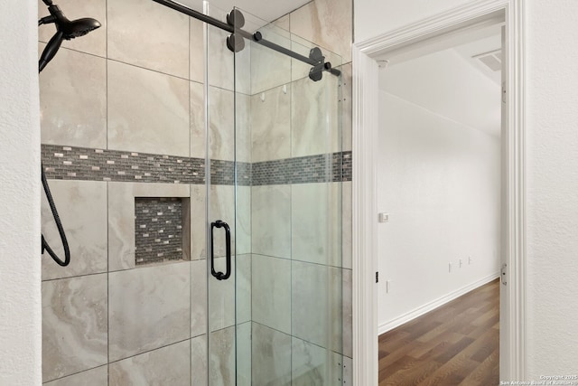 full bath with a shower stall, baseboards, and wood finished floors