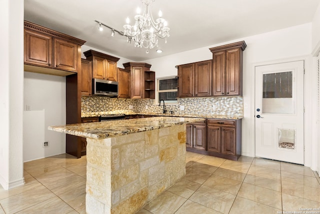 kitchen featuring open shelves, hanging light fixtures, appliances with stainless steel finishes, a kitchen island, and light stone countertops