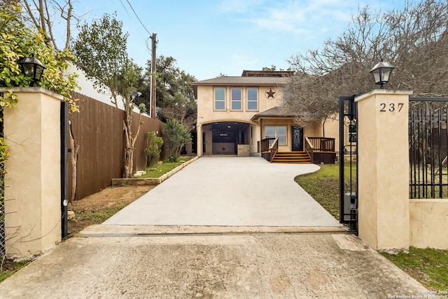 view of front facade with concrete driveway, a fenced front yard, a gate, and stucco siding