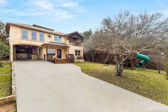 view of front of home with a playground, stucco siding, concrete driveway, a front yard, and fence