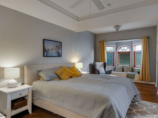 bedroom with dark wood-style floors, a ceiling fan, a raised ceiling, and crown molding