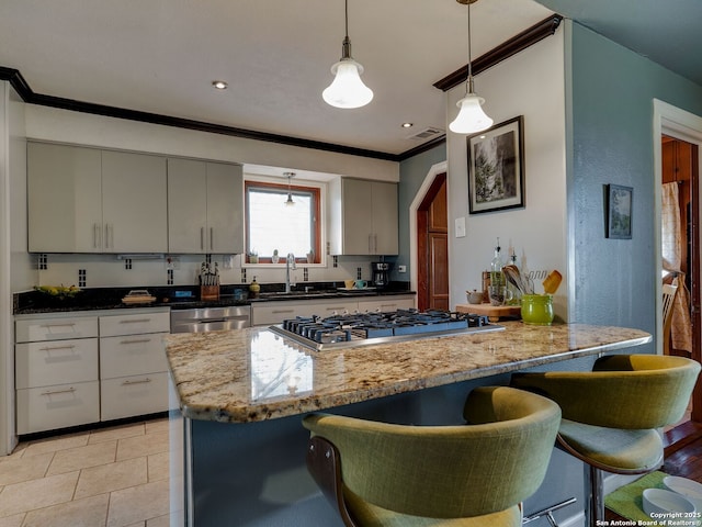 kitchen with crown molding, a sink, appliances with stainless steel finishes, a kitchen bar, and pendant lighting