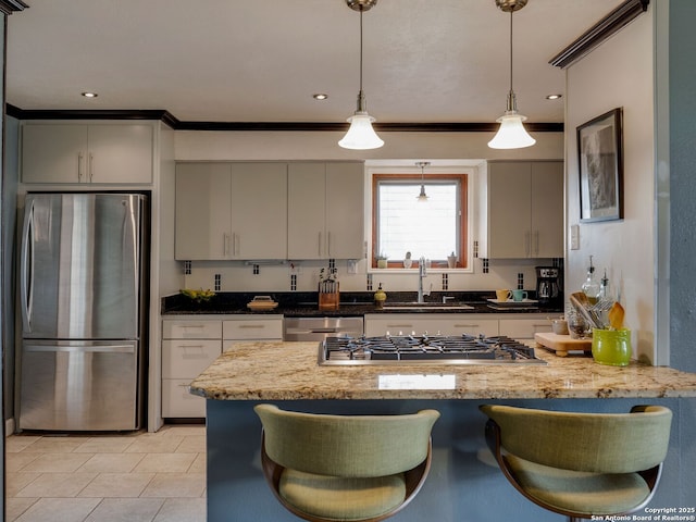 kitchen with a peninsula, a breakfast bar, a sink, appliances with stainless steel finishes, and pendant lighting