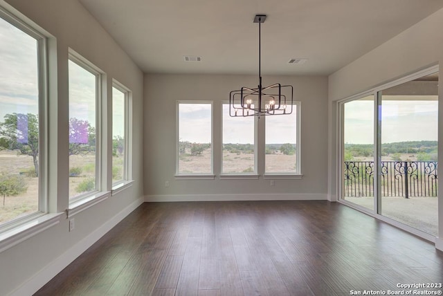 unfurnished dining area with dark wood-style floors, visible vents, and an inviting chandelier