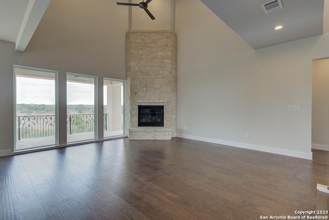 unfurnished living room with ceiling fan, a fireplace, visible vents, baseboards, and dark wood-style floors