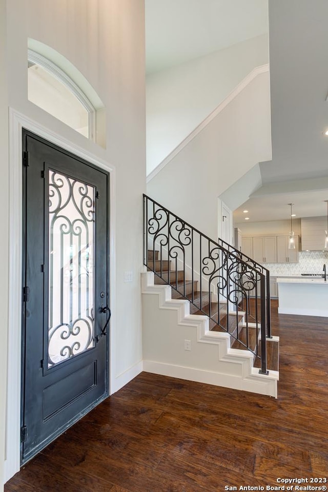 foyer with a high ceiling, dark wood finished floors, stairway, and baseboards