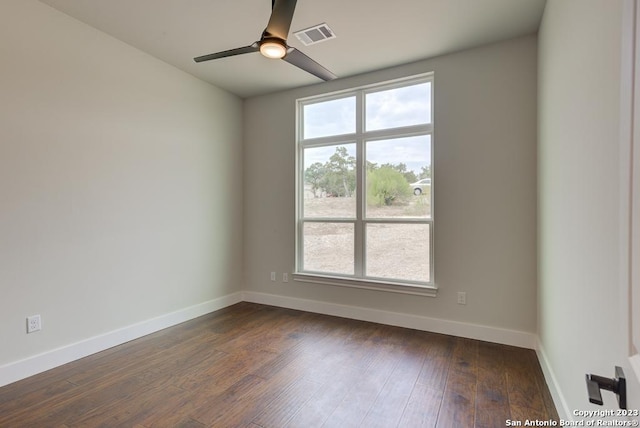 unfurnished room featuring baseboards, visible vents, dark wood finished floors, and a ceiling fan