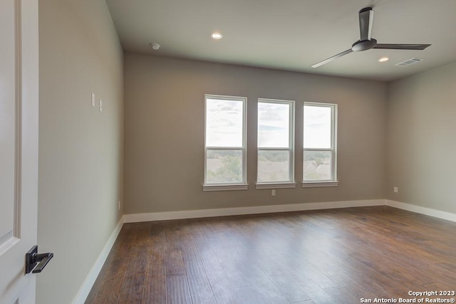 unfurnished room featuring dark wood-style floors, visible vents, baseboards, and a ceiling fan