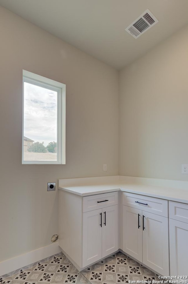 washroom with light floors, visible vents, cabinet space, electric dryer hookup, and baseboards