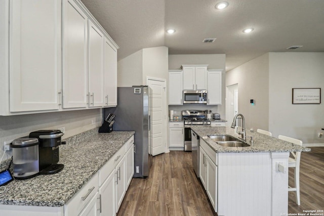 kitchen with appliances with stainless steel finishes, a sink, dark wood finished floors, and white cabinets