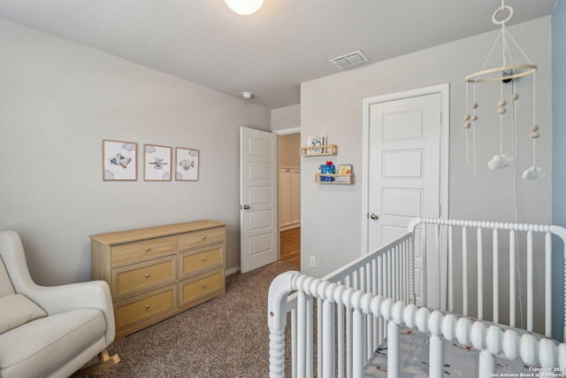 bedroom with a crib, carpet flooring, and visible vents