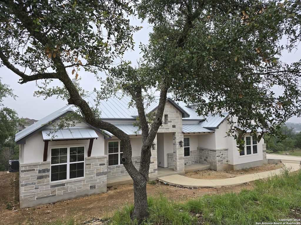 view of front of home featuring stone siding, metal roof, a standing seam roof, and stucco siding