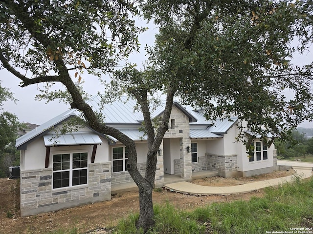 view of front of home featuring stone siding, metal roof, a standing seam roof, and stucco siding