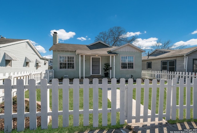 bungalow-style house with a fenced front yard and a chimney