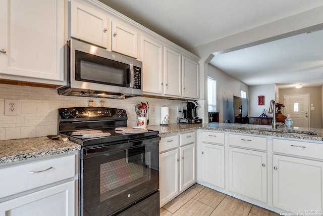 215 Quince Flower, San Antonio, TX 78253 - kitchen featuring stainless steel microwave, black range with electric stovetop, backsplash, white cabinets, and a sink
