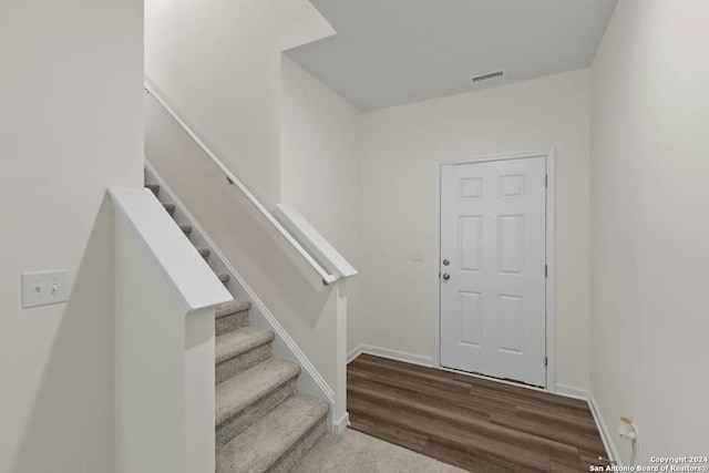 foyer entrance with baseboards, visible vents, stairway, and wood finished floors