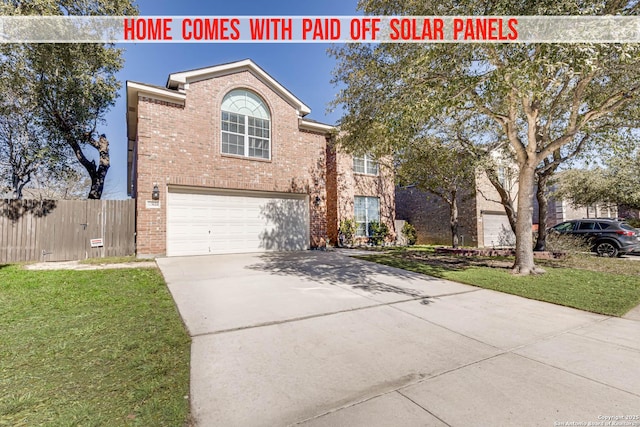 traditional home featuring brick siding, concrete driveway, an attached garage, fence, and a front lawn